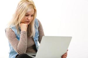 Young woman with laptop sitting on floor near light wall photo