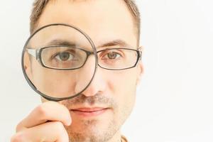 Man looking through a magnifying glass isolated on white background photo