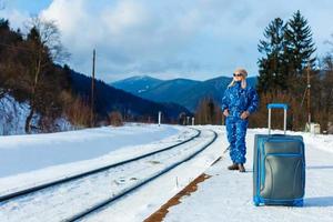 young woman in winter clothes waiting for her train photo