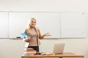 Portrait of pretty teacher holding notepads in a classroom in school photo