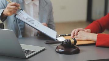 Business and lawyers discussing contract papers with brass scale on desk in office. Law, legal services, advice, justice and law concept picture with film grain effect video