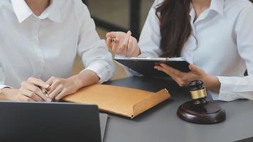 Business and lawyers discussing contract papers with brass scale on desk in office. Law, legal services, advice, justice and law concept picture with film grain effect video