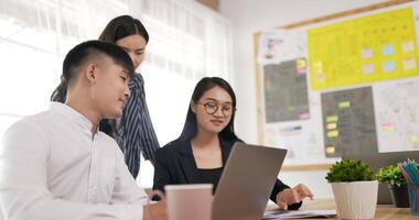 kvinna mentor tränare portion asiatisk kvinna glasögon och manlig anställd med företags- programvara. thai kollegor arbetssätt på projekt tillsammans på grupp möte. chef hört klient. video