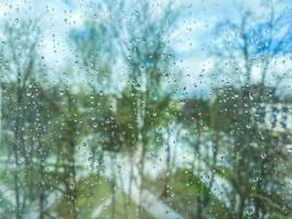 reflection in glass, window of a multi-storey building. raindrops on the glass. texture, background. against the backdrop of trees, plants and greenery in the rain photo