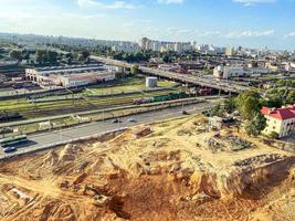 campo de construcción hecho de arena y barro. un lugar para construir una base, un campo con rastros de grandes equipos de construcción. estacionamiento cercano con autos, autos y una cisterna foto