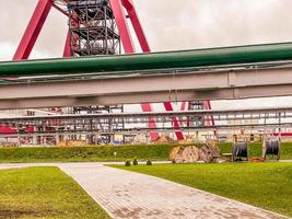 construction site of an industrial complex. building a mine for mining around the world. green and metal gray pipes against the background of a red metal mine photo