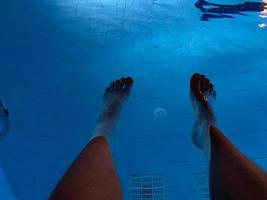 ariel view of mans feet as he is about to dive into a clear blue swimming pool photo