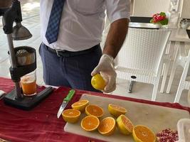 A man makes freshly squeezed orange juice with a manual juicer at an all-inclusive hotel in a touristic warm tropical country paradise resort on vacation photo