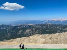 instructor with a child and a backpack for flight and a helmet is preparing to fly with a parachute against the backdrop of high rocky mountains, the theme of outdoor activities and extreme sports photo
