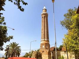 area in a hot, tropical country. small houses with tiled roofs against the backdrop of green palm trees. in the center of the square there is a high tower with a spire photo