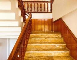 escaleras empinadas en el hotel. pasamanos de madera, escalones de mármol para el descenso de turistas al vestíbulo. escalera de azulejos, hermoso acabado sólido foto