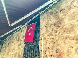 wall in a residential area. a red flag of turkey is fixed on a sheet of plywood. next to a curved metal grille photo