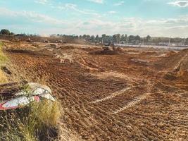 campo de construcción hecho de arena y barro. un lugar para construir una base, un campo con huellas de un tractor en tierra fresca. al lado hay una señal de tráfico hecha de metal foto