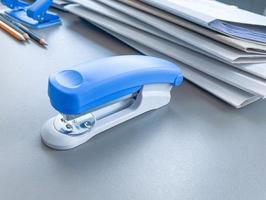 Photo of blue stapler put on the table in office, stapler is a device used in schools or offices.