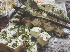 snacks on the table in the hotel. great selection of food for tourists for lunch. cheese plate with tongs for serving in portions. cheese with herbs photo