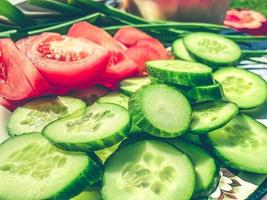 plato de verduras. los pepinos y los tomates se cortan en círculos finos. fibra dietética, alimentos saludables para el intestino, verduras para ensalada. comida vegana vitamínica, vegetales naturales de granja foto