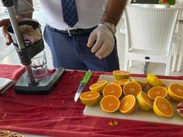 A man makes freshly squeezed orange juice with a manual juicer at an all-inclusive hotel in a touristic warm tropical country paradise resort on vacation photo