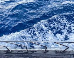 caminar sobre el mar abierto. el yate está equipado con laterales metálicos para la seguridad de los turistas. vacaciones en países cálidos. olas azules del mar, espuma blanca burbujeante foto