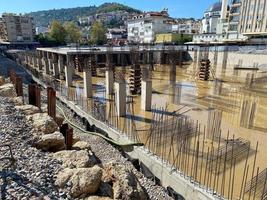 construcción de un edificio de estructura monolítica, cimientos inacabados con columnas de hormigón armado en un lugar de construcción con un pozo inundado foto