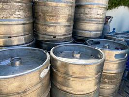 Old Aluminum Beer keg. Wall of used and scratched stainless steel beer barrels or kegs. Stacked in a row large silver or metallic colour alcohol barrels or containers photo