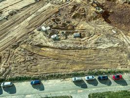 campo de construcción hecho de arena. un lugar para construir una base, un campo con rastros de grandes equipos de construcción. aparcamiento cercano foto