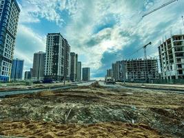 construction of flowerbeds, footpaths, creation of infrastructure. construction of a new neighborhood in the city. erection of tall, multi-storey buildings from concrete blocks photo