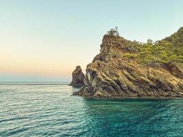 green mountains with plants above in the sea. a rock in the water, a tiny island for sailors. tourist resort. travel in hot countries photo
