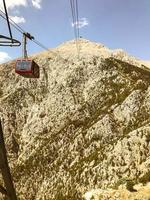 mountains in a hot, tropical country against a blue sky. green plants grow on the mountains. cable car with a wagon carries tourists to the top photo