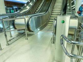 escalator in the underpass. rise to different metro stations. huge metal steps for the trip up. nearby turnstiles with neon signs photo