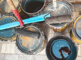 construction site. there are paint cans on the ground. on them lies a wali in black paint. preparation of materials for application on walls, decorative plaster photo