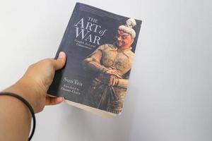 West Java, Indonesia on July 2022. A hand is holding a book called The Art of War by Sun Tzu. photo