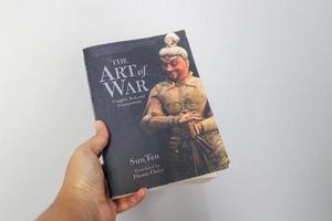 West Java, Indonesia on July 2022. A hand is holding a book called The Art of War by Sun Tzu. photo