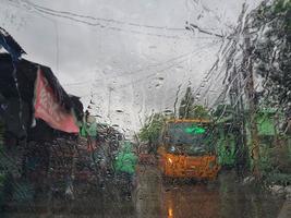 Jakarta, Indonesia in July 2022. The condition from inside a car, where the windshield of the car was raining and in front of the car there was a yellow school bus passing by photo