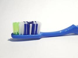 Isolated white photo of a plastic toothbrush that has been used several times. This toothbrush has a blue handle.