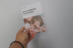 West Java, Indonesia on July 2022. A hand holding Manulife's Insurance Handbook for life and health insurance photo