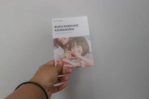 West Java, Indonesia on July 2022. A hand holding Manulife's Insurance Handbook for life and health insurance photo