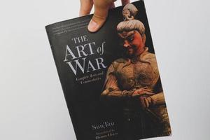 West Java, Indonesia on July 2022. A hand is holding a book called The Art of War by Sun Tzu. photo