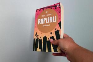 West Java, Indonesia on July 2022. A hand is holding a novel called Rapijali second edition, Being, written by the famous writer Dee Lestari photo