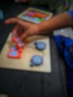 Defocused blurry shot of a boy's hand holding a wooden puzzle photo