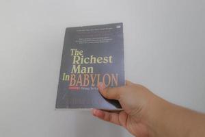 West Java, Indonesia on July 2022. A hand is holding a novel The Richest Man in Babylon. photo