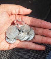 A hand is holding several rupiah coins. These coins are usually used to give to packs of people who help cross the vehicle or direct them to turn around. photo