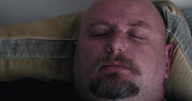homem de barba dormindo na cama e acordando abrindo os olhos video
