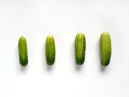 Four cucumbers from small to big in a row in white background photo