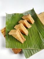 en línea tofu frito sobre hojas de plátano y una tabla de cortar de madera. aislado sobre fondo blanco foto