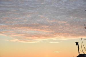 Sunset landscape in the countryside in winter. The setting sun behind the roof of the house in the evening. The disk of the sun and the evening sunset. Yellow pink beautiful sunset and sky. photo