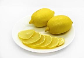frutos amarillos maduros y jugosos de limones en un plato blanco. primer plano de limones en rodajas. deliciosos limones para el té. rodajas de limon foto
