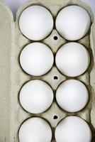 Fresh white chicken eggs in a paper bag. White eggs in a package on a white background. Eggs from the store. photo