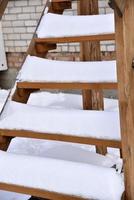 Wooden stairs at the house in the snow in winter. Beautiful staircase in the snow. Snow on the steps. photo