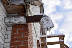 Spontaneous ventilation pipe in a house with icicles and ice in winter. The ventilation pipe is insulated in winter weather. photo