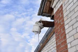 Spontaneous ventilation pipe in a house with icicles and ice in winter. The ventilation pipe is insulated in winter weather. photo